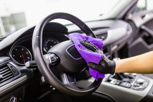 Person in gloves cleaning steering wheel