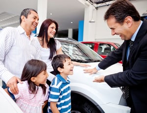 Happy family with the dealer buying a new car